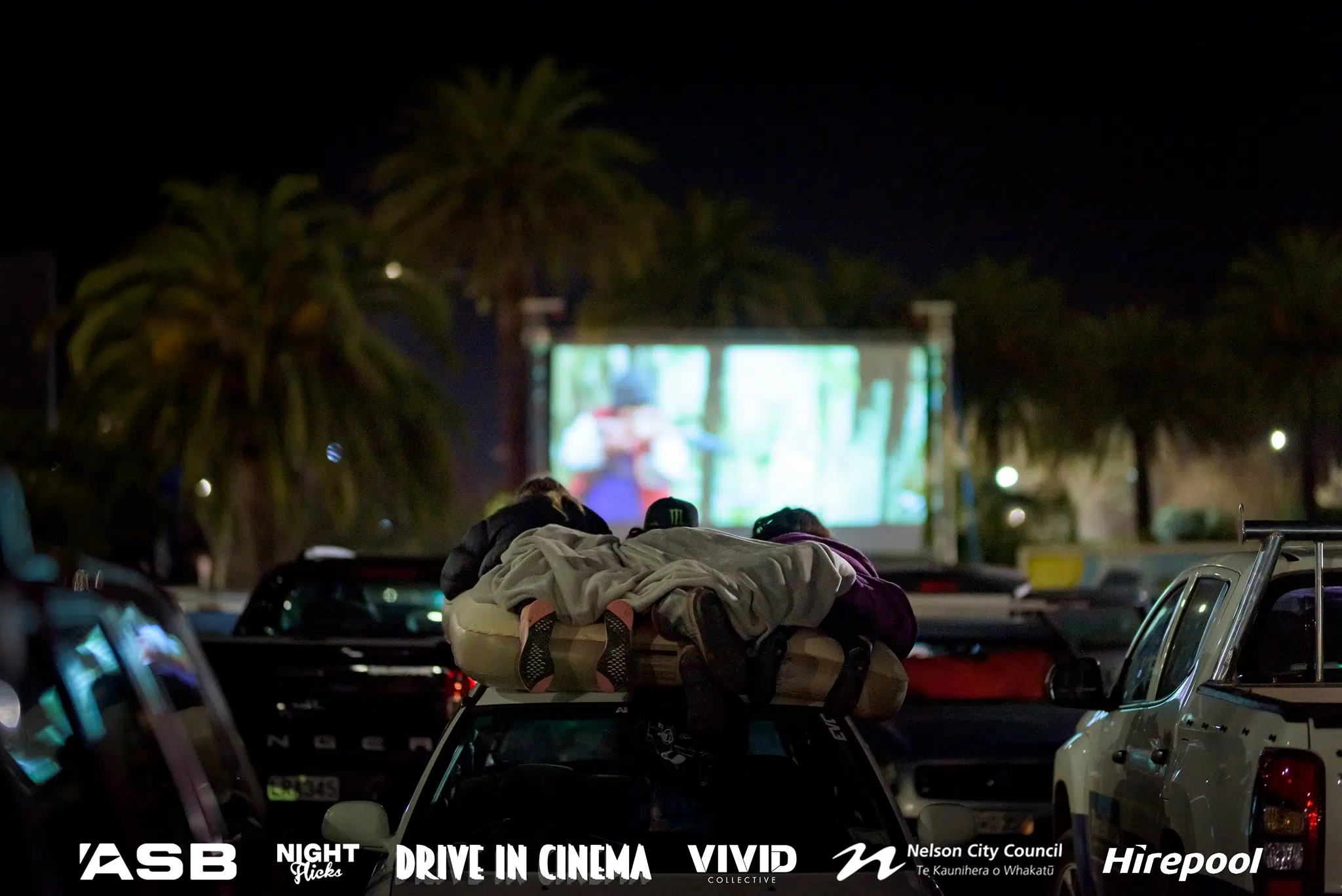 Family at a drive in cinema watching from the roof of their vehicle